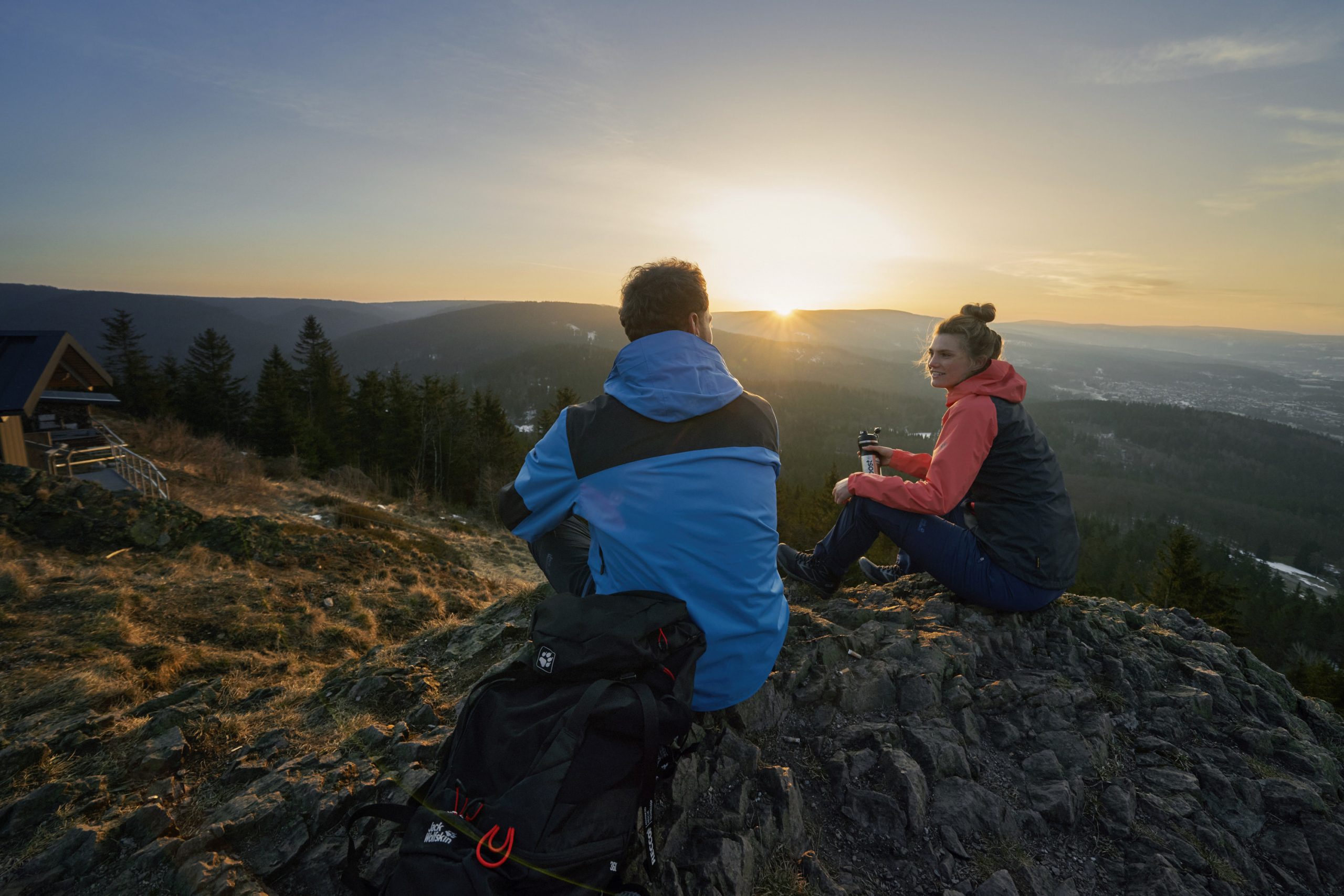 Outdoor-Fotograf Köln: Wanderer auf einem Berggipfel während des Sonnenaufgangs.